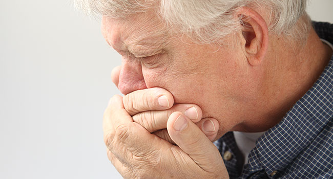 Hombre tapándose la boca por náuseas.