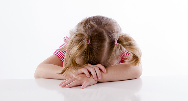 Niña agachando su cabeza.