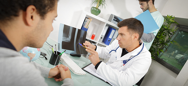 Doctor revisando unos rayos-x con paciente enfrente.