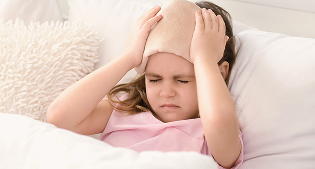 Niña acostada con dolor de cabeza.